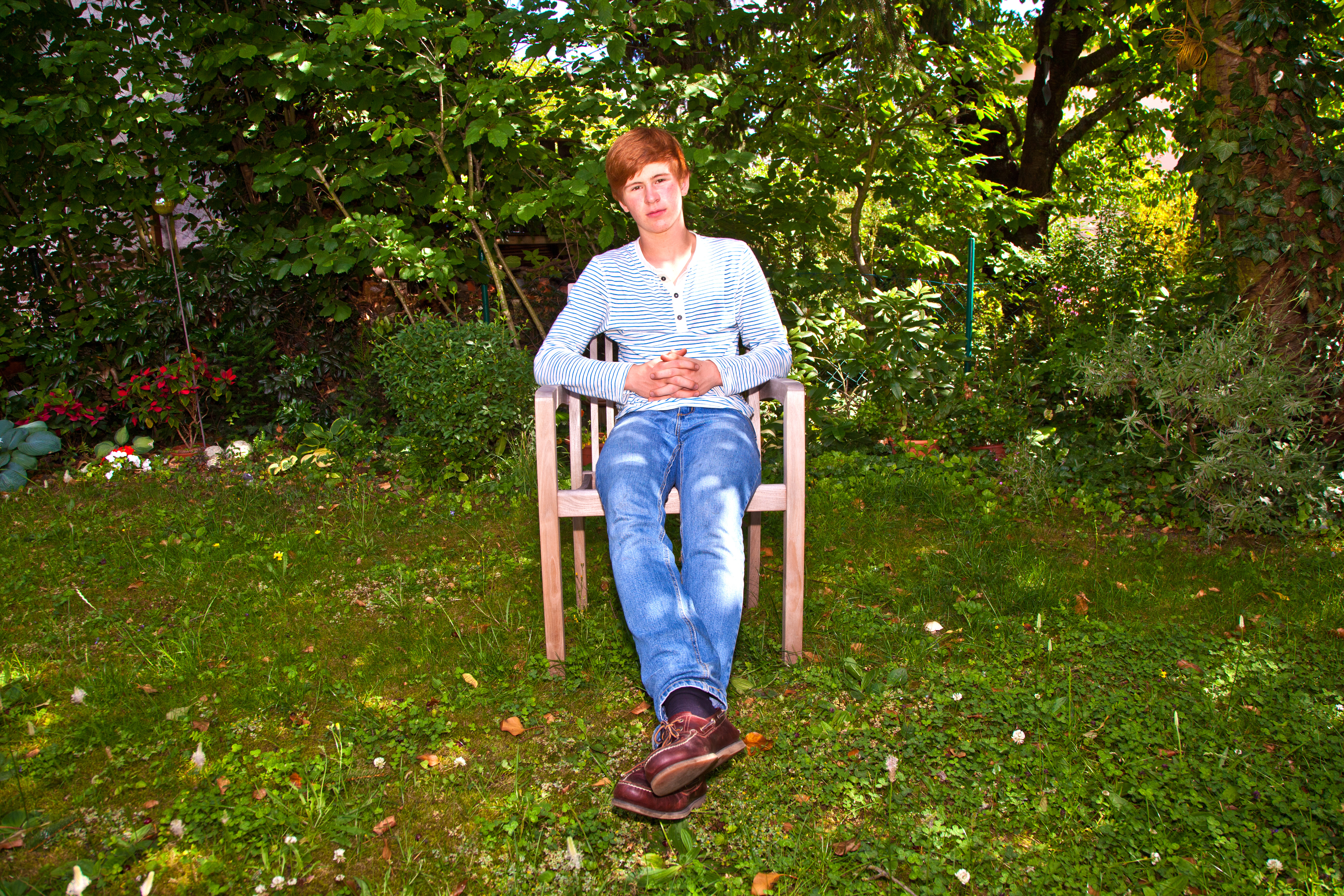 boy sitting on an armchair in his garden
